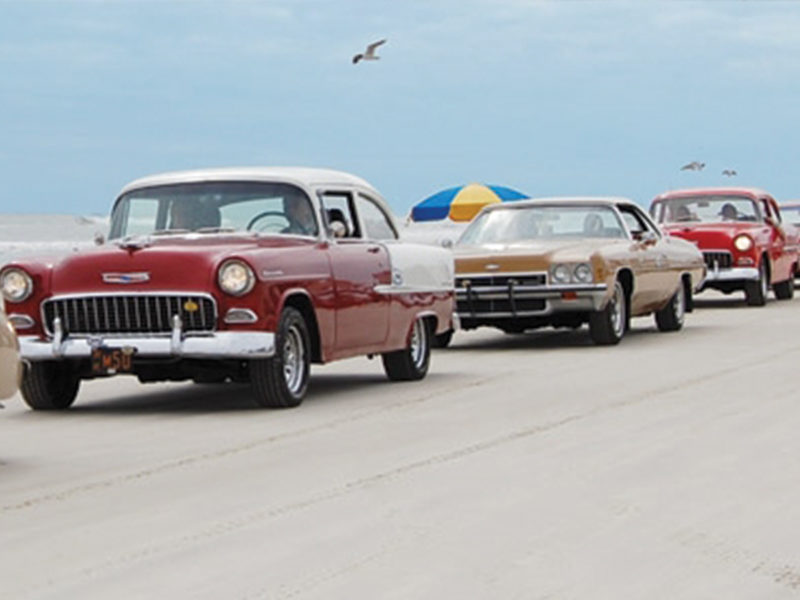 vintage chevrolet cars driving at the beach